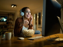 Young woman having fun while eating popcorn and watching movie