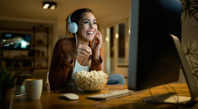 Young woman having fun while eating popcorn and watching movie